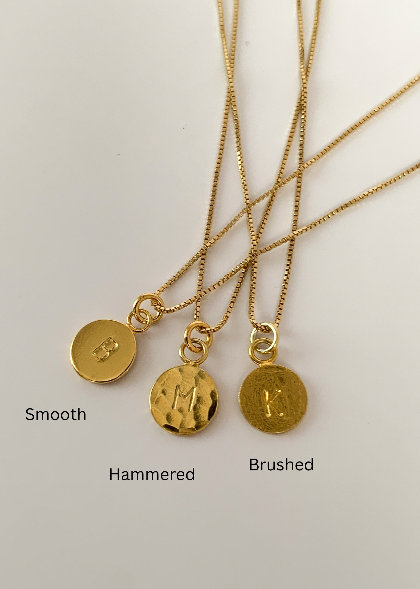 Three gold necklaces with different finishes on a white background.